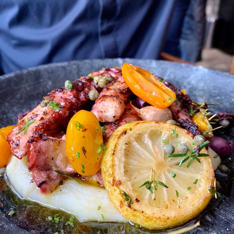 Plato de pulpo a la parrilla con verduras y rodaja de limón