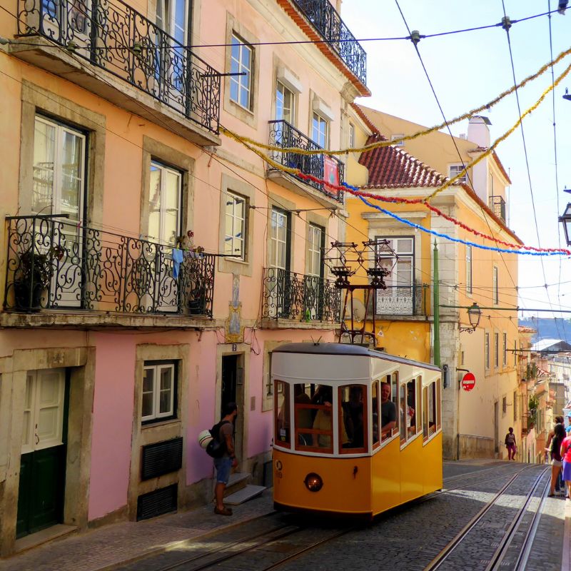 Calle típica de Lisboa adornada con guirnaldas con uno de sus característicos tranvias amarillos